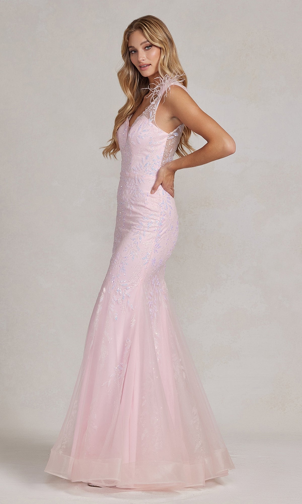 A woman in a fitted light pink Feather-Strap Long Prom Dress (Nox Anabel T1208) with lace, sequin, and glitter mermaid details stands in profile against a neutral background.